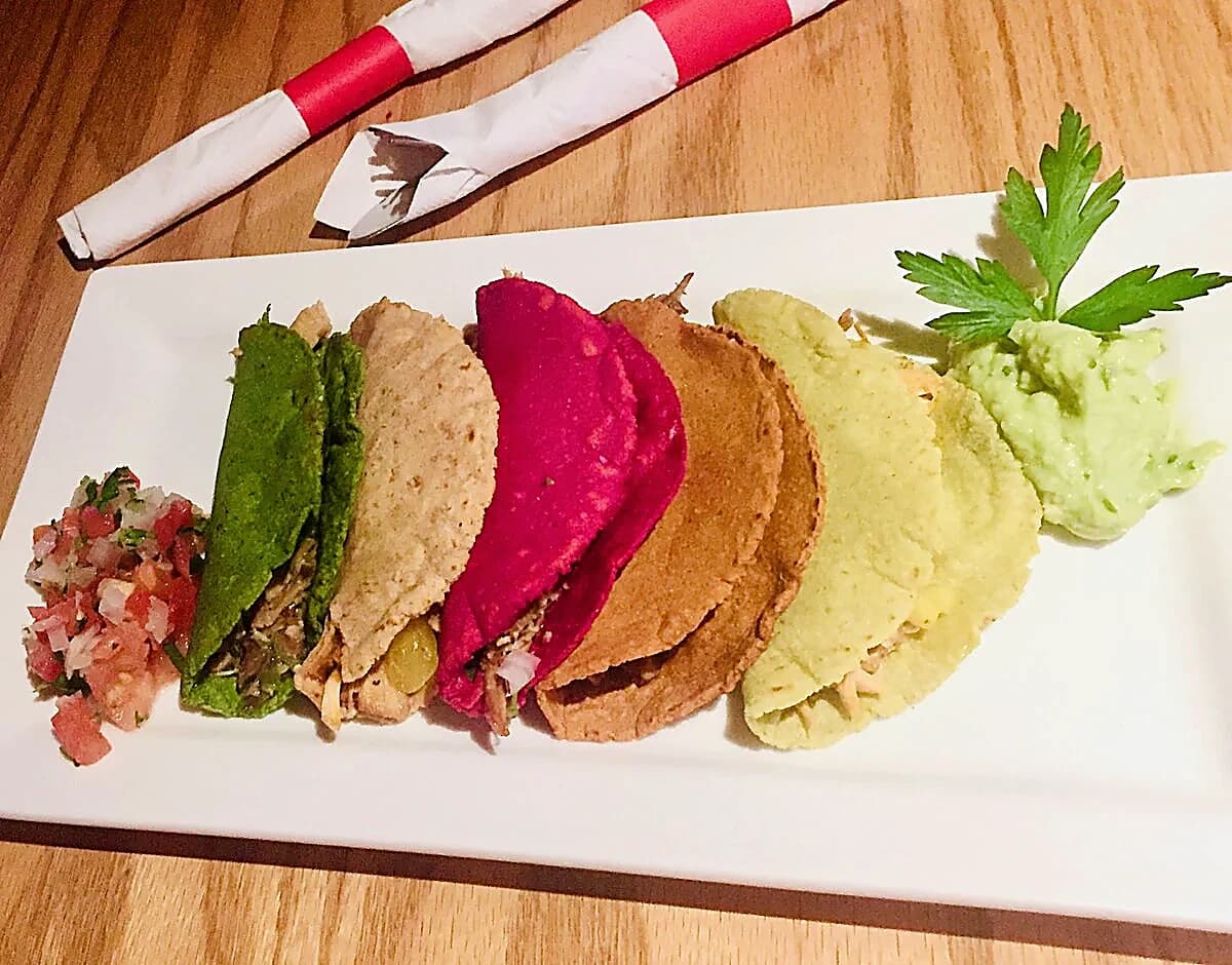 Five colourful house-made tortillas plated with salsa and guacamole
