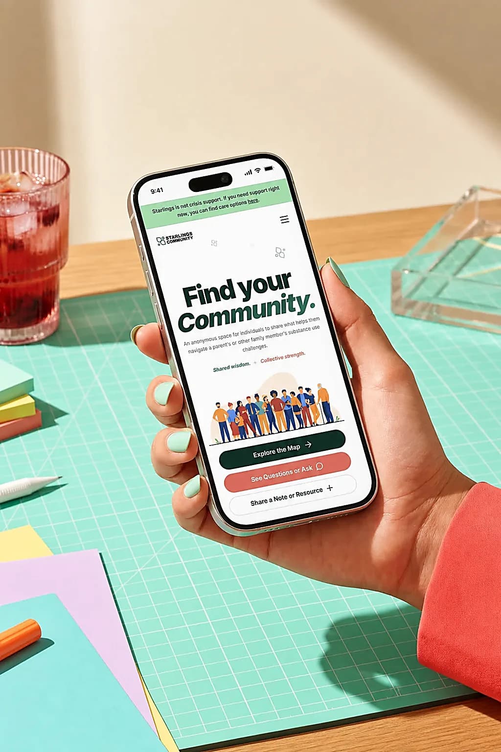 A person holding a phone showing the Starlings Support Map homepage