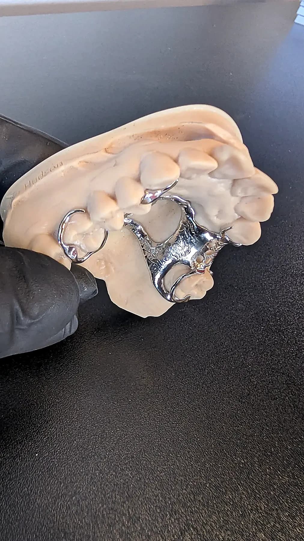 Close detail of the palatal strap and clasp work on a finished upper cobalt-chrome framework